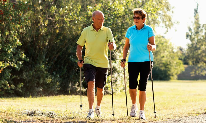 Un homme et une femme heureux de pratiquer la marche nordique sous le soleil